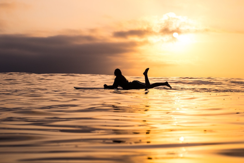 Woman on surfboard with sunset